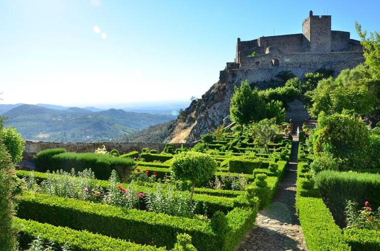 um jardim com um castelo no topo de uma colina em VillasMC no Alpalhão
