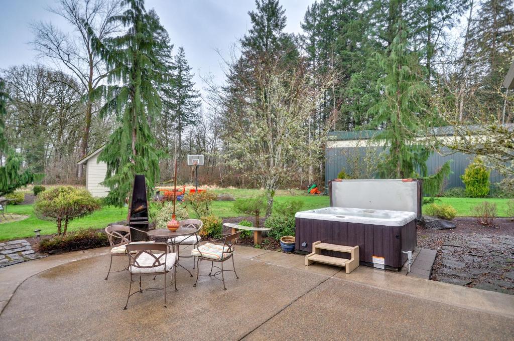 eine Terrasse mit einem Tisch und Stühlen sowie einem Whirlpool in der Unterkunft Spacious Oregon Home with Hot Tub, Fire Pit and Grill! in Hillsboro