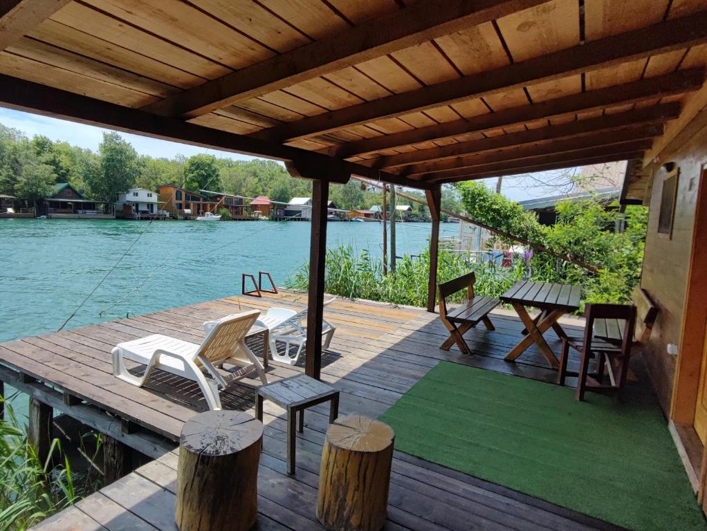 une terrasse en bois avec des chaises et une table de pique-nique sur l'eau dans l'établissement Coso House Ada Bojana, à Ulcinj
