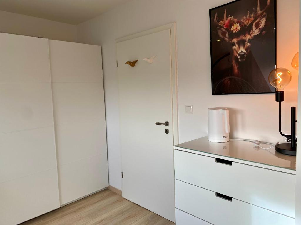 a white kitchen with white cabinets and a door at gemütliches Dachgeschoss in Bonn