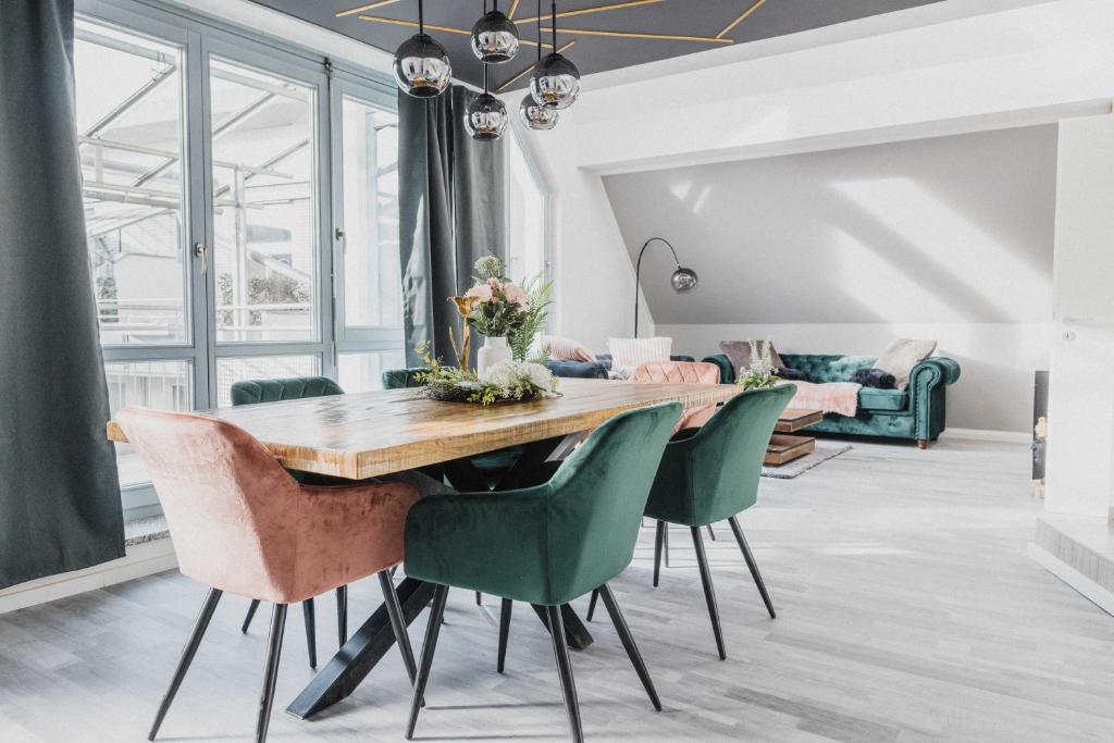 a dining room with a wooden table and green chairs at Luxury 4 Bedroom Apartment/Therme Erding/Parking in Erding