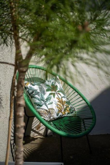 a green chair with a pillow sitting next to a tree at Lovely house with courtyard and terrace near canal du Midi in Trèbes