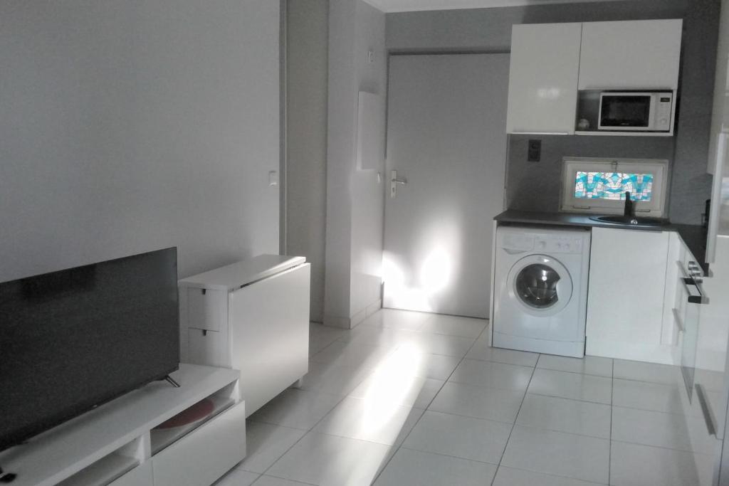 cocina blanca con lavadora y microondas en 1 bedroom apartment in a residence with a swimming pool and a parking spot, en Vallauris