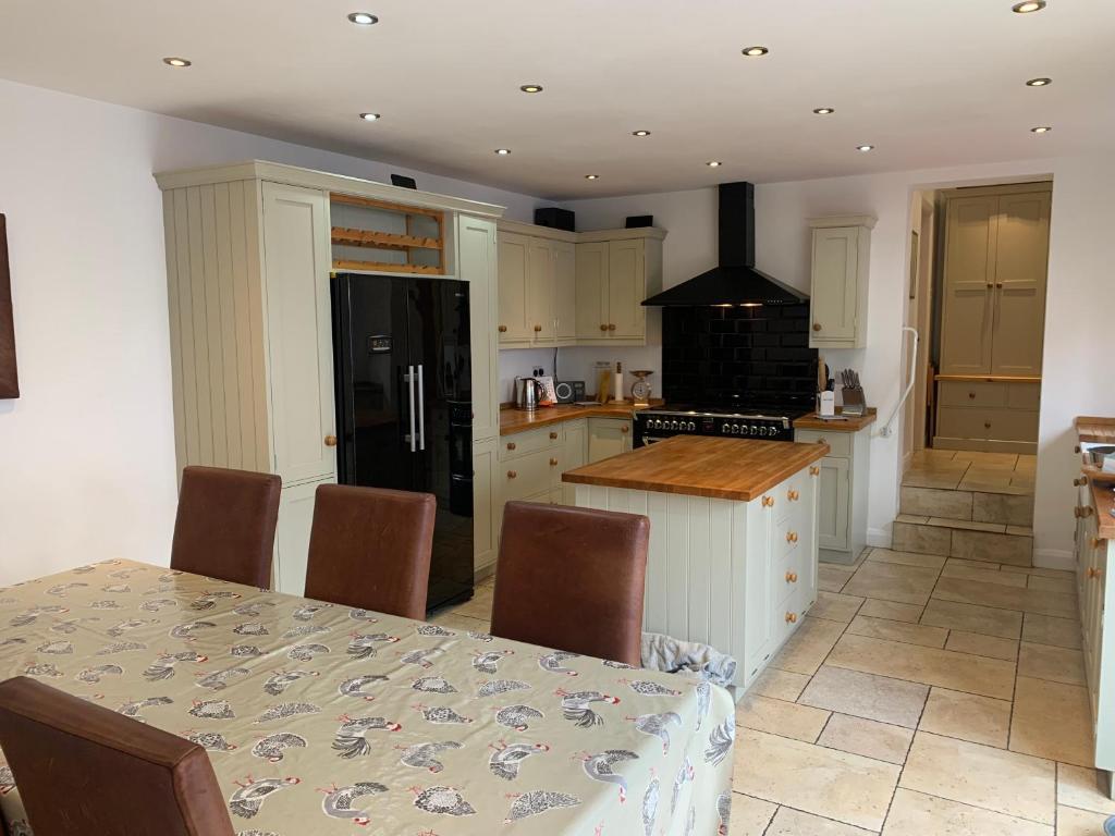 a kitchen with a table and a black refrigerator at Stable Cottage in Tettenhall
