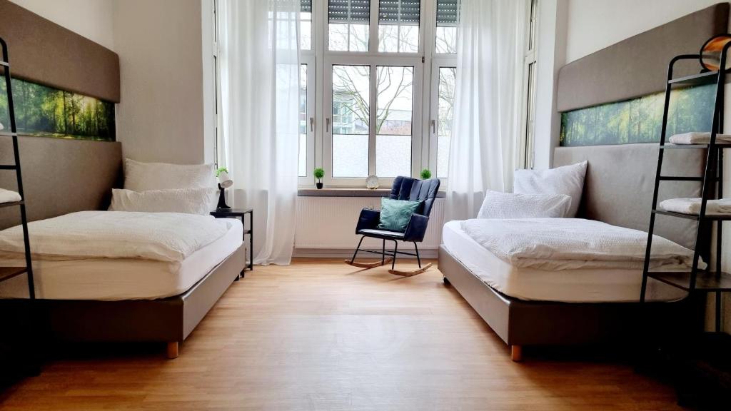Duas camas num quarto com uma cadeira e uma janela em 135m²-Apartment I max. 8 Gäste I Zentral I Küche I Balkon I Parken I WLAN em Lünen