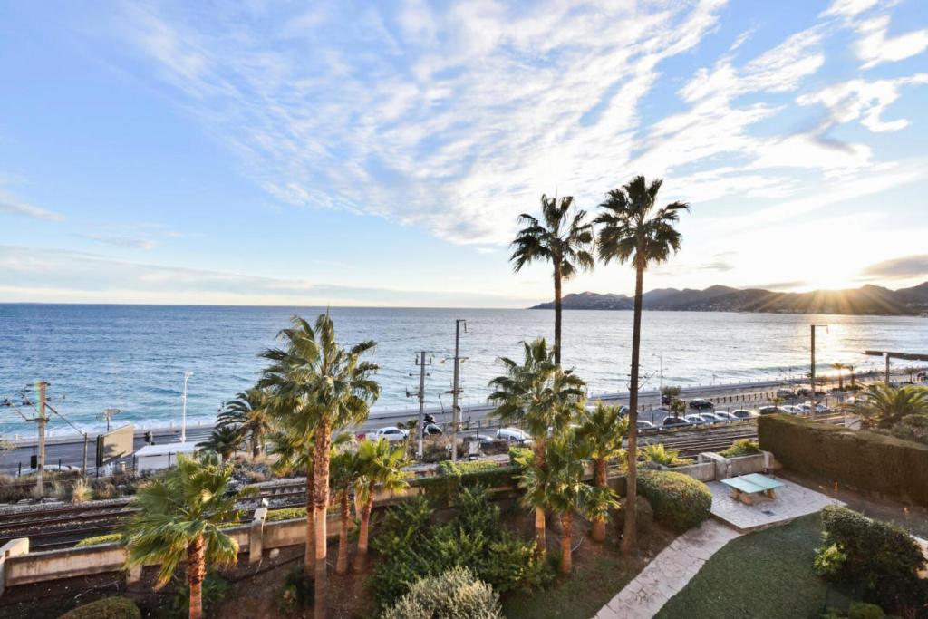 une vue sur une plage avec des palmiers et l'océan dans l'établissement Résidence Cannes Verrerie - maeva Home - 2 Pièces 5 Personnes Confort MAE-3572, à Cannes