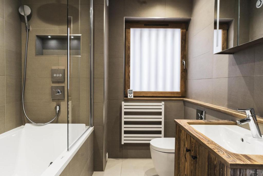a bathroom with a tub and a toilet and a sink at Résidence Le Bercail - Chalets pour 12 Personnes 224 in Saint-Martin-de-Belleville