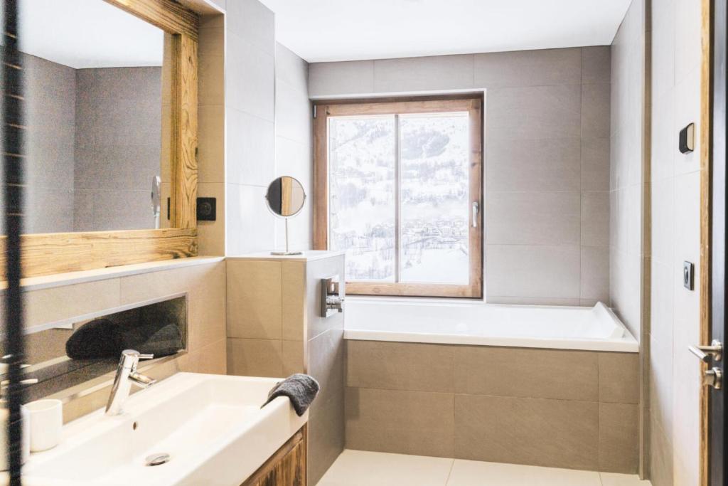 a bathroom with a sink and a tub and a window at Résidence Le Bercail - Chalets pour 12 Personnes 224 in Saint-Martin-de-Belleville