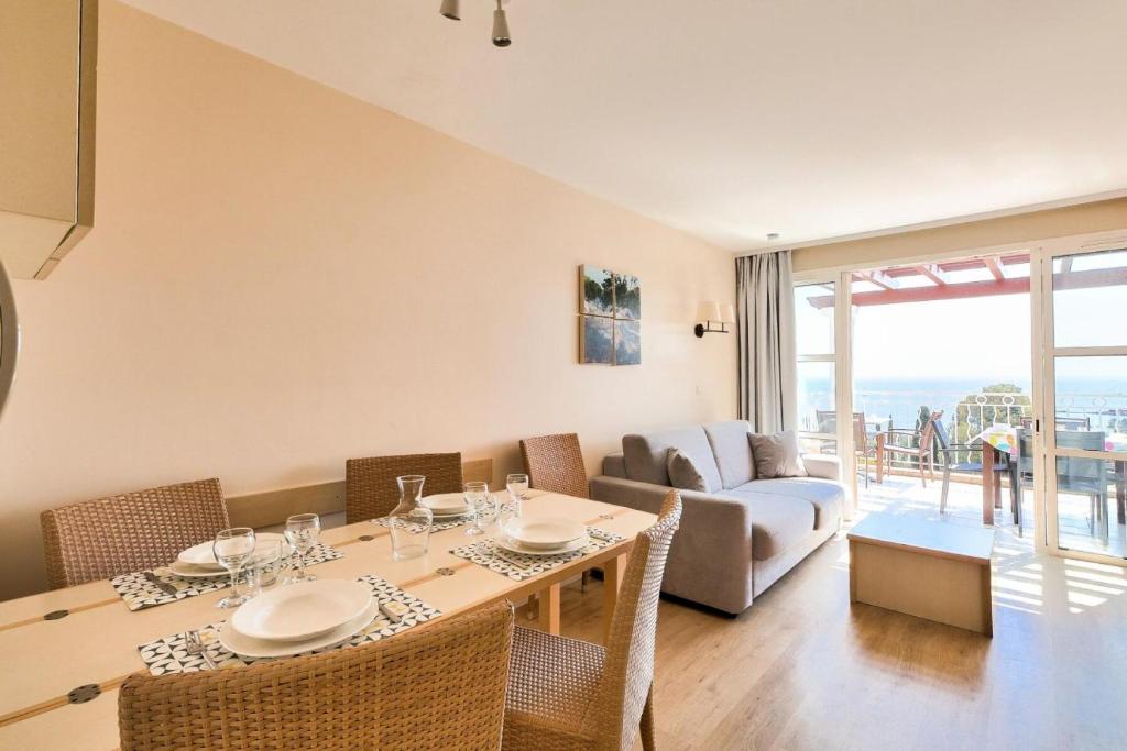 a dining room with a table and chairs and a couch at Résidence le Village de Cap Esterel - maeva Home - Appartement 2 pièces 6 p 26 in Saint-Raphaël
