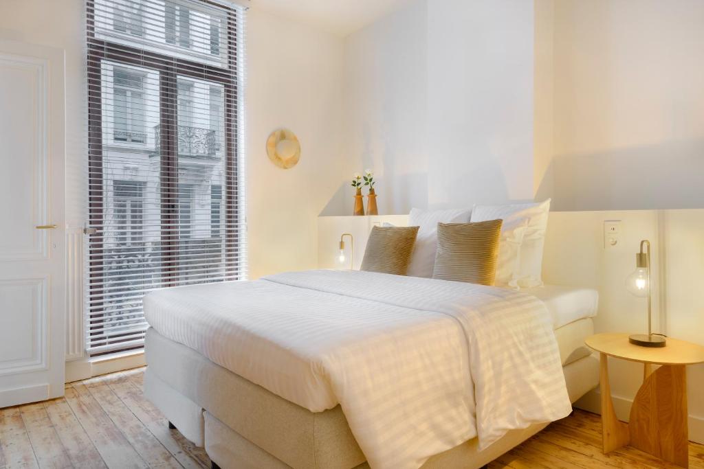 een witte slaapkamer met een groot bed en een raam bij The 1894 Residence by Domani Hotels in Antwerpen
