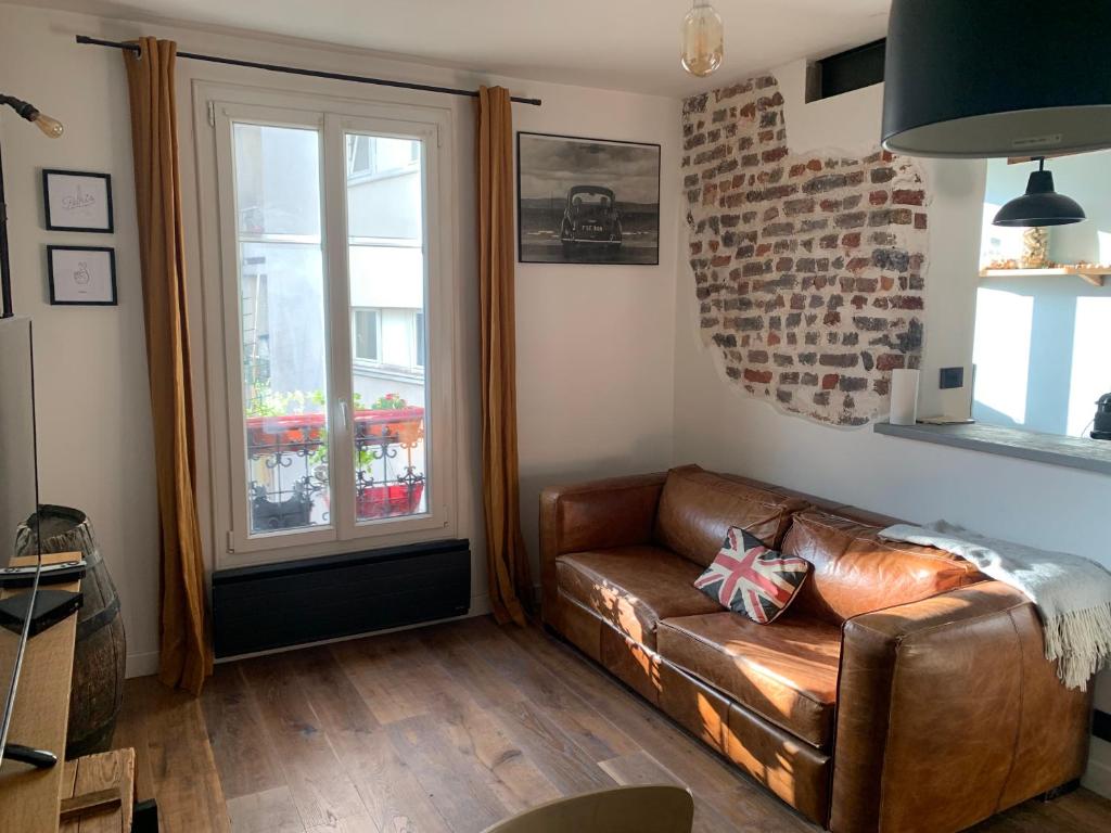 un salon avec un canapé en cuir et une fenêtre dans l'établissement L'appart sur le canal, à Paris