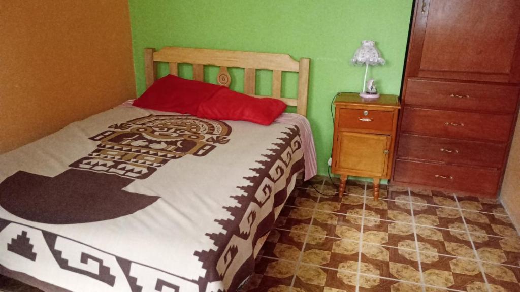- une chambre avec un lit doté d'un oreiller rouge et d'une commode dans l'établissement Teach Huaraz Peru, à Huaraz