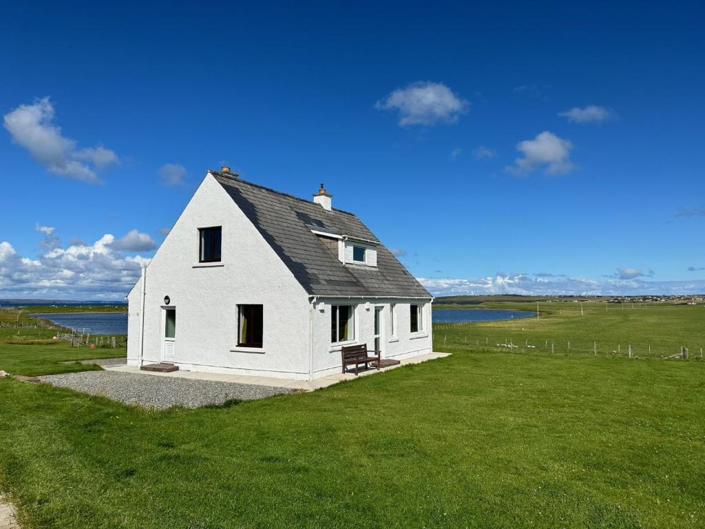una piccola casa bianca su un prato di Braighe Cottage a Stornoway