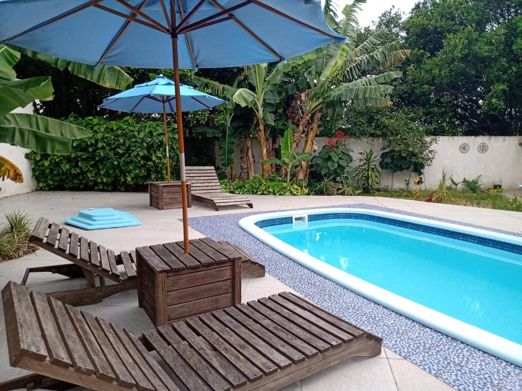 ein Pool mit zwei Sonnenschirmen und Stühlen neben einem Pool in der Unterkunft Férias!! Inspire-se e Renove! 7km centroMar Torres RS in Torres