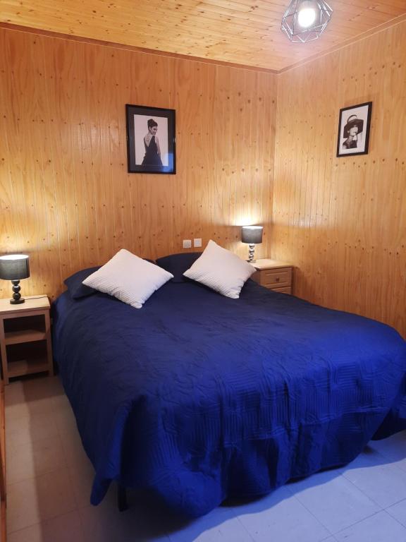 een slaapkamer met een groot blauw bed met 2 lampen bij Normandie chalet N70 piscine lac golf in Saint-Manvieu-Bocage