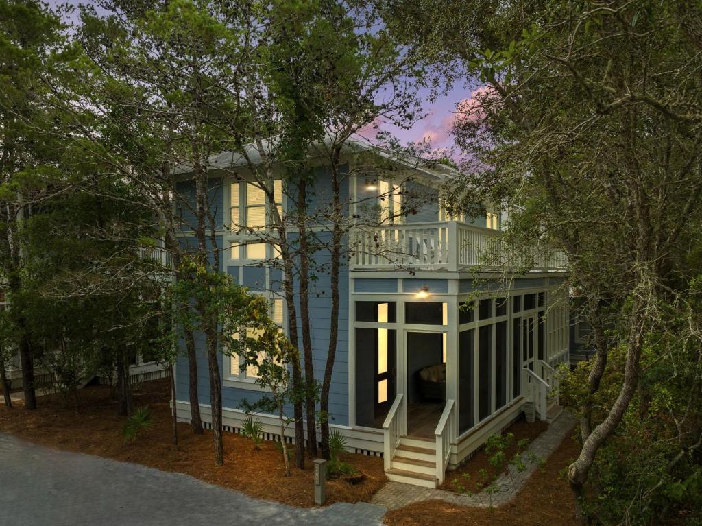a blue house with a white porch in the woods at Shirleys Temple in Seagrove Beach