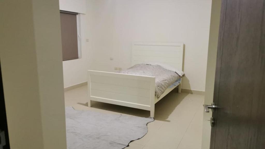 a bedroom with a bed in a white room at Al Andulcia Airport Road Complex مجمع الاندلسية طريق المطار 