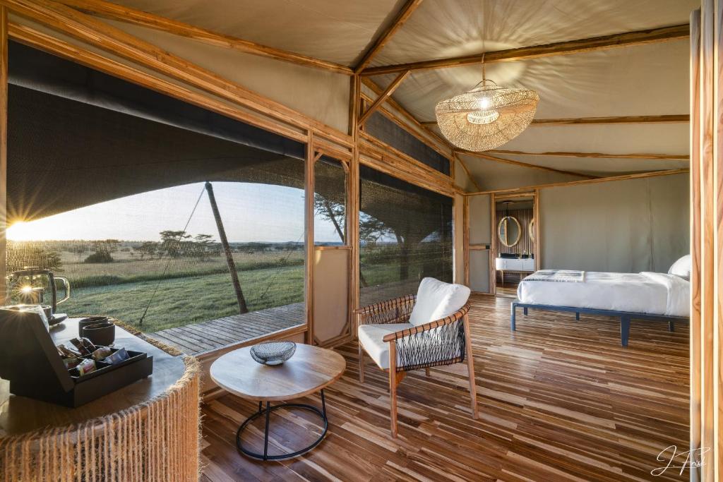 - une chambre dans une tente avec un lit et un canapé dans l'établissement Anantya Serengeti, à Serengeti