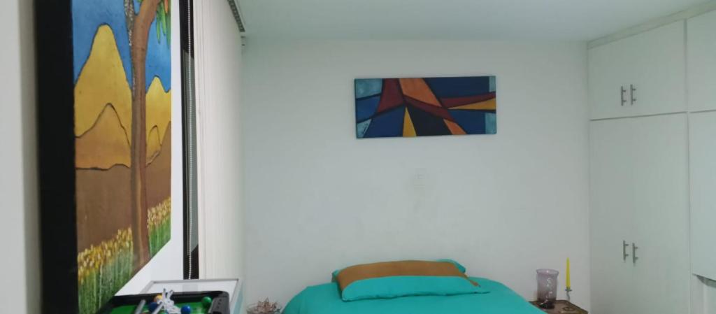 um quarto com uma cama e um quadro na parede em Casa Raíces em Quito