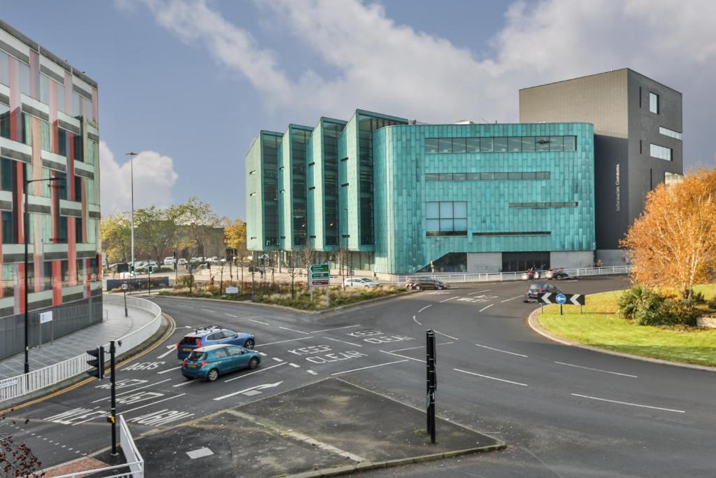 a city intersection with a street with cars in front of a glass building at George House - 3BSleep9 Close to Train station,Uni,Pond Forge,City Centre,Free Parking in Sheffield