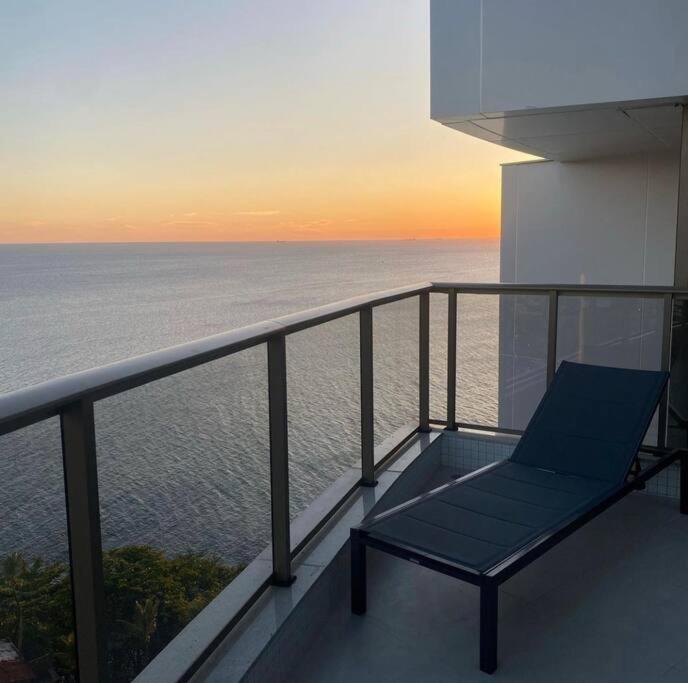 a blue chair sitting on a balcony overlooking the ocean at Apartamento em Ondina com acesso à praia (Beach Class Salvador) in Salvador