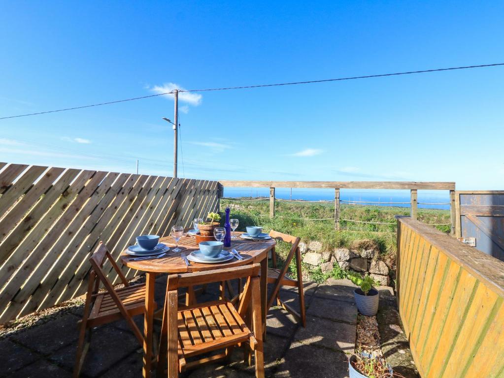 een tafel en stoelen op een balkon met uitzicht op de oceaan bij Kerensa ha-Kres in Sennen