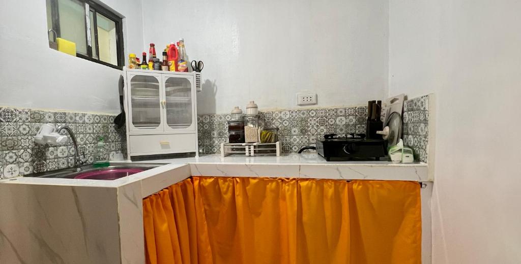 a kitchen with a sink and an orange curtain at Lanara House in Magalang