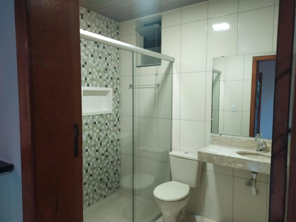 a bathroom with a toilet and a sink and a mirror at Suites Cantinho de MInas in Lavras Novas