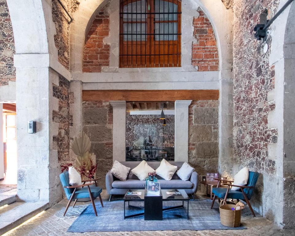 eine Terrasse mit einem Sofa, Stühlen und einem Kamin in der Unterkunft Casa de la Luz Hotel Boutique in Mexiko-Stadt