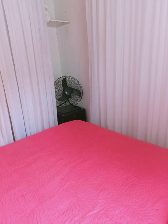 ein Schlafzimmer mit einem rosa Bett und einem Stuhl in der Unterkunft Toca in Pipa