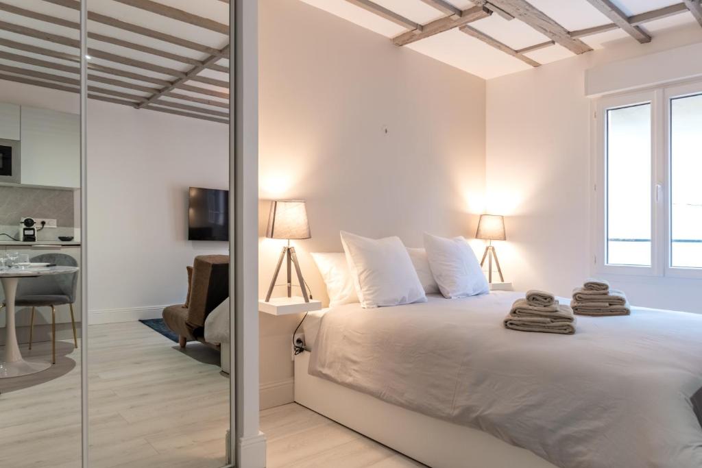 a bedroom with a white bed with a glass door at Villa Caron - Studios haut de gamme hyper centre in Rouen