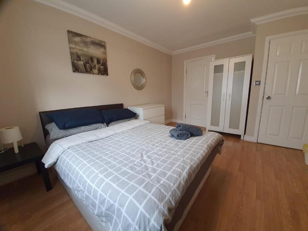 Schlafzimmer mit einem Bett mit einer blauen und weißen Bettdecke in der Unterkunft London Ilford Rooms in Goodmayes