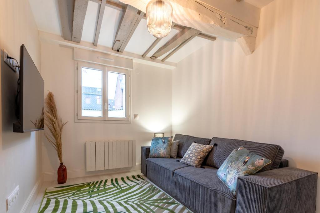 uma sala de estar com um sofá cinzento e uma janela em Villa Caron - Appartements haut de gamme avec chambre hyper centre em Rouen