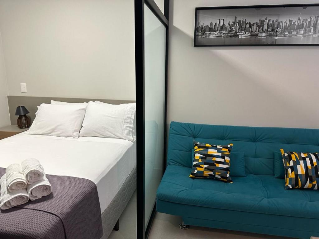 1 dormitorio con 1 cama y 1 sofá azul en LOFTS CARIJOS CENTRO BH, en Belo Horizonte