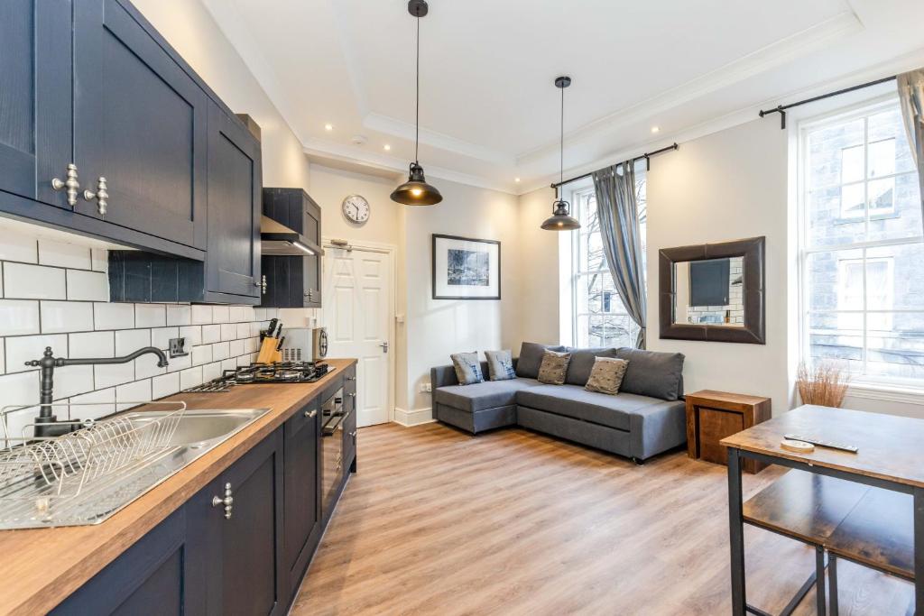 een keuken en een woonkamer met een bank bij REFURBISHED QUIET 3 BEDROOM FLAT BY HIGH STREET, TRAMS and BUSES - 30 MINS WALK TO CENTRE in Edinburgh