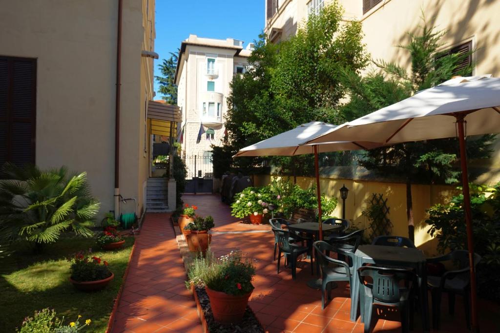 an outdoor patio with tables and chairs and an umbrella at Green Hotel in Rome