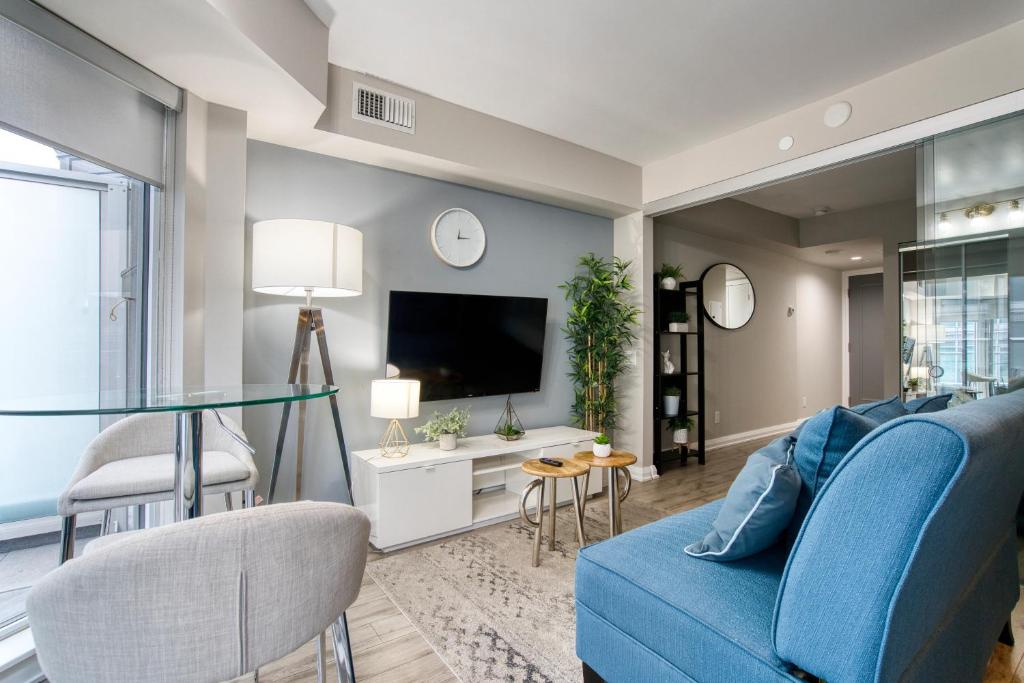 uma sala de estar com um sofá azul e uma televisão em Modern 1 bedroom sleeps 3 Yorkville STK em Toronto