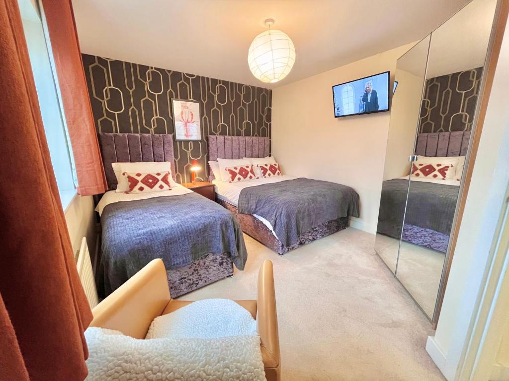 a room with two beds and a mirror at Payler House Sheffield-WiFi -Large Parking Space-cozy 4 bedrooms in Sheffield