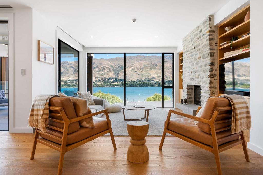 a living room with two chairs and a fireplace at Lakeside Luxury 2 Bedroom Apartment in Wanaka