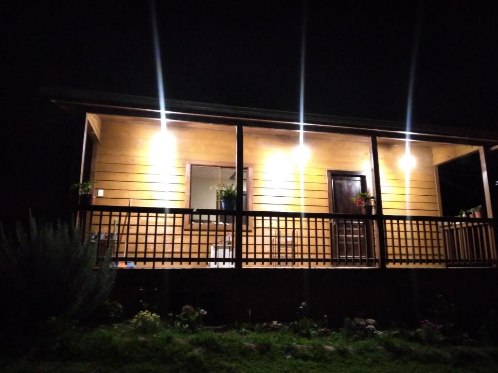 a house with lights on a balcony at night at Rancho Valle del Rio in Cuenca