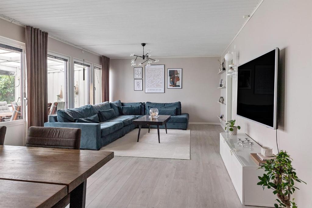 uma sala de estar com um sofá azul e uma televisão em Radhus med 5 min bilavstånd till centrum & strand em Halmstad