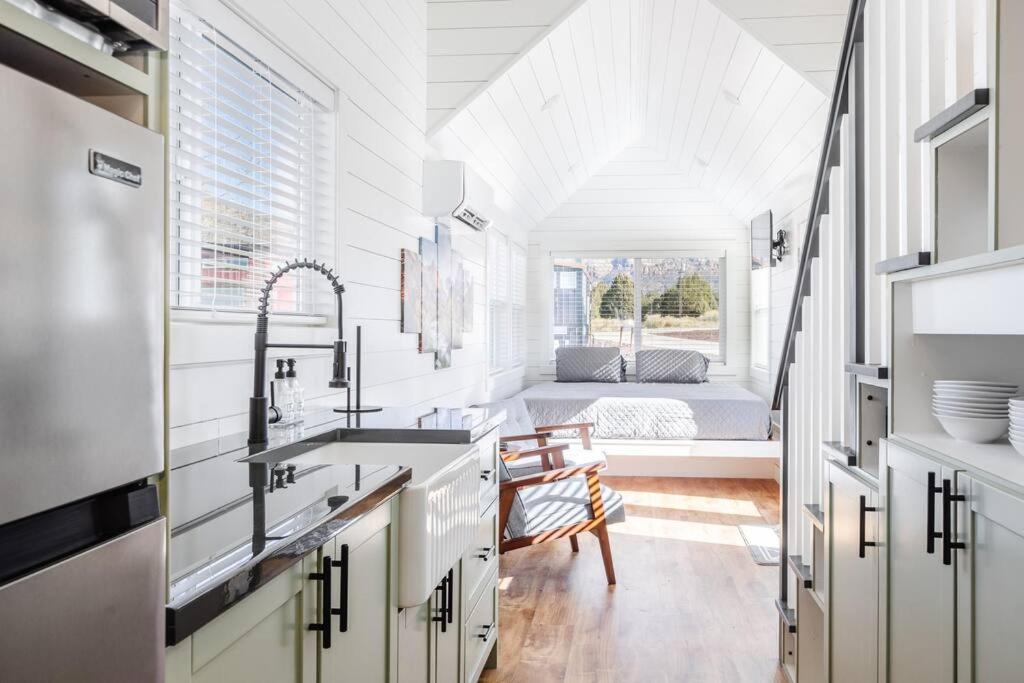 a white kitchen with a sink and a bedroom at Zion Tiny Home, Hot Tub, Red Rock Views in Apple Valley