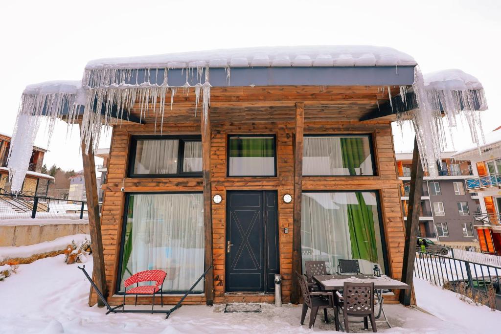une petite maison avec une porte d'entrée dans la neige dans l'établissement Kokhta Cottage, à Bakuriani