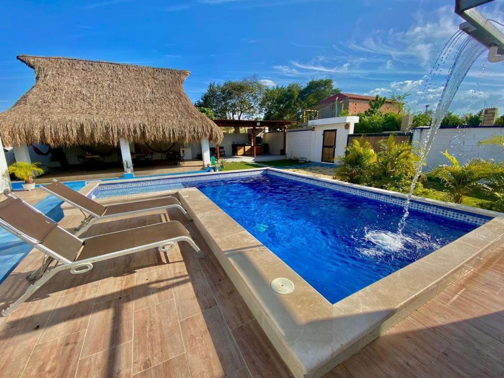 a swimming pool with a straw umbrella and a resort at HERMOSA CASA FINCA EN TURBACO in Turbaco