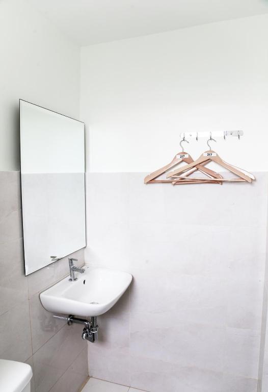 a white bathroom with a sink and a mirror at Travelbee Airport Inn in Mactan