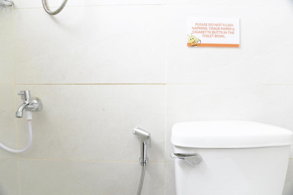 a bathroom with a toilet and a sign on the wall at Travelbee Airport Inn in Mactan