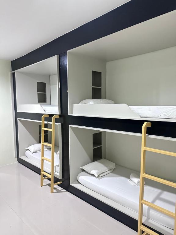 a room with three bunk beds and two chairs at Travelbee Airport Inn in Mactan