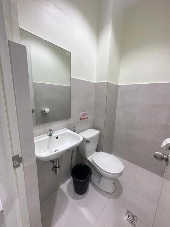 a bathroom with a sink and a toilet and a mirror at Travelbee Airport Inn in Mactan