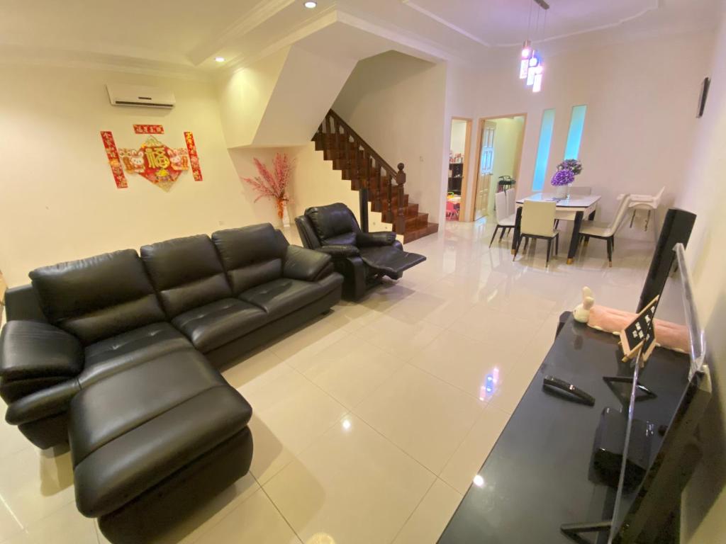 a living room with a black leather couch and a table at 139 Homestay 13 Mins From kuching Airport Baby Friendly Spacious Home in Kota Samarahan