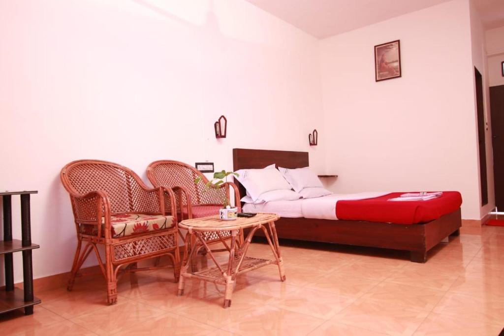 a bedroom with a bed and chairs and a table at Rays Inn Thekkady in Thekkady